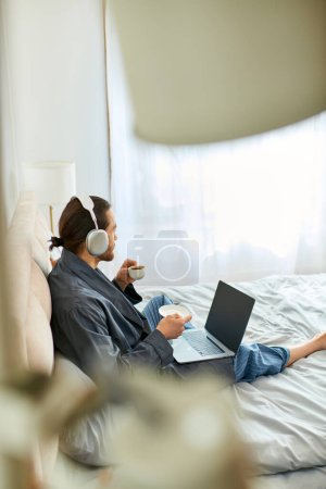 Un hombre y un hombre se sientan en una cama con ordenadores portátiles abiertos, centrándose en el trabajo y la comunicación.