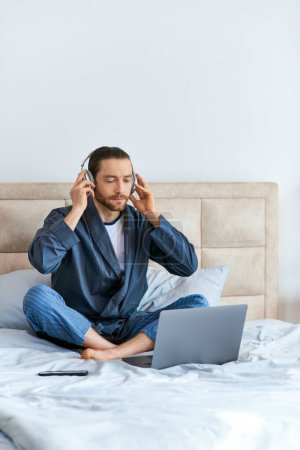 Photo for A man is seated on a bed, engrossed in music. - Royalty Free Image