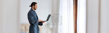 Photo for A man in a bathrobe using laptop. - Royalty Free Image