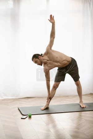 A handsome man gracefully practices a yoga pose on a mat at home.