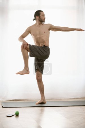 Téléchargez les photos : Beau homme pratique le yoga sur un tapis à la maison. - en image libre de droit