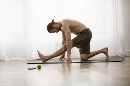 Téléchargez les photos : Un bel homme pratique une posture de yoga sur un tapis à la maison le matin. - en image libre de droit