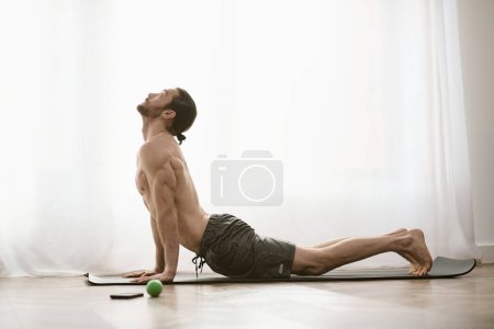 Foto de At-home morning yoga session with a focused man practicing on a mat. - Imagen libre de derechos