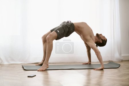 Yoga zu Hause, während ein Mann eine herausfordernde Pose auf seiner Matte übt.