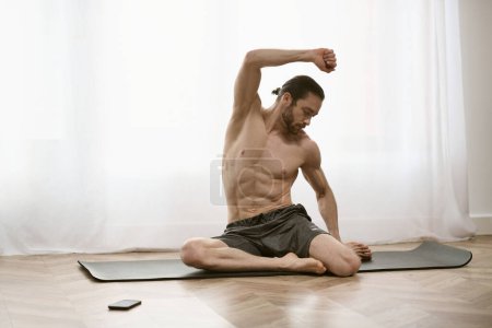 Hemdloser Mann auf Yogamatte lässt Muskeln spielen.