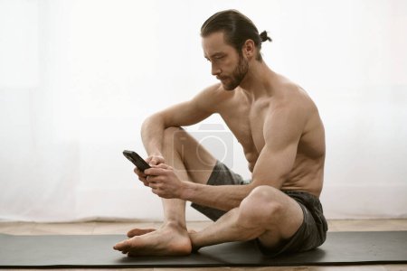 Photo for Man doing yoga, focused on phone screen. - Royalty Free Image