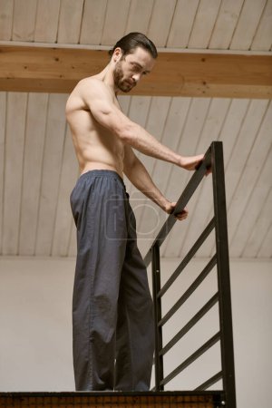 Un bel homme se tient au sommet de l'escalier pendant sa routine matinale.