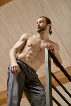 A shirtless man balances on a stair rail.