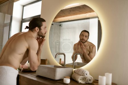 Téléchargez les photos : Bel homme toilettage en face de miroir de salle de bains à la maison. - en image libre de droit