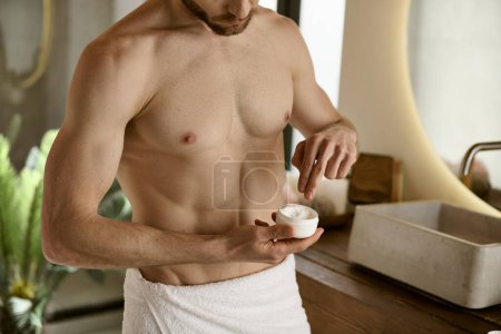 Foto de Un hombre en una toalla aplicando crema. - Imagen libre de derechos