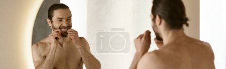 A handsome man brushes his teeth in front of a mirror.