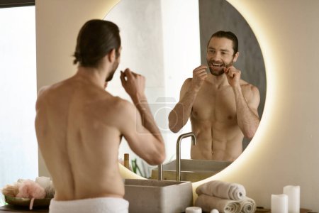 Un hombre usando hilo dental frente a un espejo durante su rutina matutina.