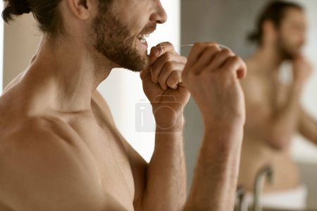 Handsome man brushing teeth in bathroom mirror.