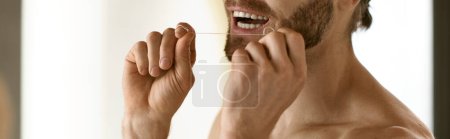 Foto de El hombre sin camisa cepilla los dientes frente al espejo, parte de su rutina matutina. - Imagen libre de derechos