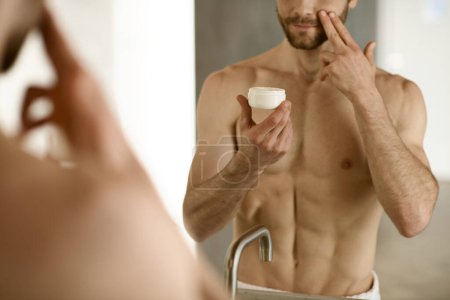 A man applying cream in front of a mirror during his morning routine.