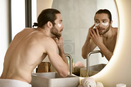 Téléchargez les photos : Un homme qui applique des patchs devant un miroir. - en image libre de droit