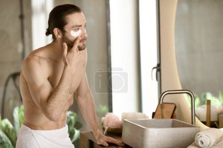 Téléchargez les photos : Homme appliquant des patchs admirant sa routine de soins matinaux dans le miroir. - en image libre de droit