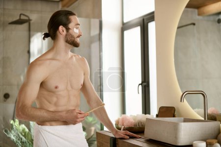 Un homme dans une serviette se tient à un lavabo de salle de bains, effectuant sa routine de soins de la peau du matin.