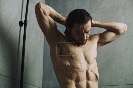 Shirtless man engaging in his morning standing in a shower.