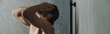 Un homme torse nu prenant une douche tout en prenant soin de sa routine matinale.