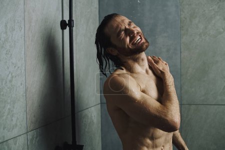 Schöner Mann, ohne Hemd, steht zum Duschen bereit und konzentriert sich auf seine morgendliche Routine.