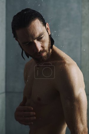 Hemdloser Mann genießt eine erfrischende Dusche in seinem Badezimmer.