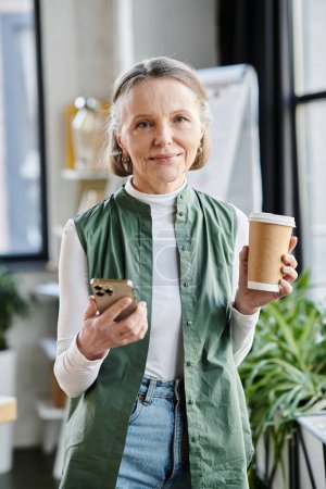 Photo for Businesswoman holds coffee cup and phone. - Royalty Free Image