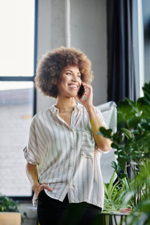 Femme d'affaires afro-américaine parlant sur un téléphone portable dans un bureau.