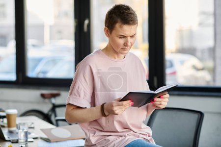 Photo for Beautiful businesswoman luxuriates at a table, engrossed in a book. - Royalty Free Image