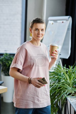A businesswoman in a pink shirt enjoys a moment with a cup of coffee.