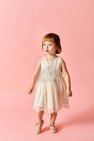 Foto de Una linda chica en un vestido blanco se levanta con gracia sobre un vibrante fondo rosa. - Imagen libre de derechos