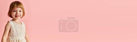 Photo for Little girl in white dress stands against vibrant pink backdrop. - Royalty Free Image