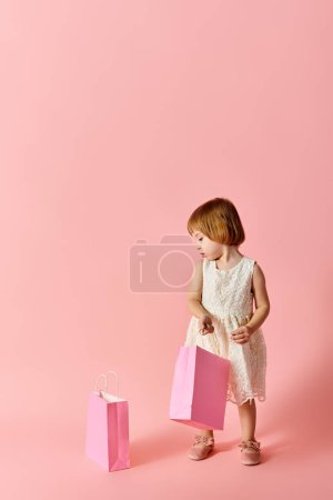 Entzückendes Mädchen im weißen Kleid mit Einkaufstaschen auf rosa Hintergrund.