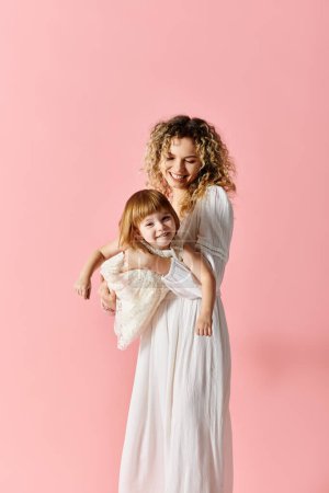 Photo for A mother with curly hair holds her baby on a pink background. - Royalty Free Image
