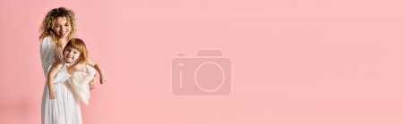 Photo for A woman holds a baby against a pink backdrop. - Royalty Free Image