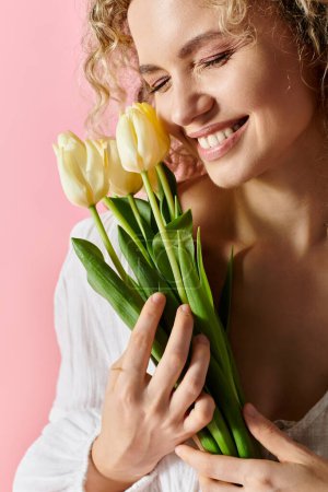 Eine Frau mit lockigem Haar hält freudig einen Strauß Tulpen in der Hand.