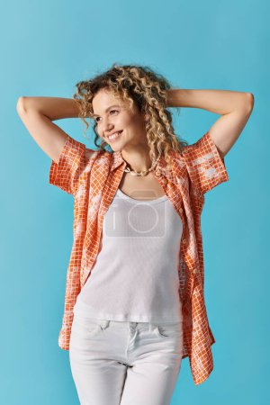 Téléchargez les photos : Femme aux cheveux bouclés en jean blanc et chemise orange frappant une pose. - en image libre de droit
