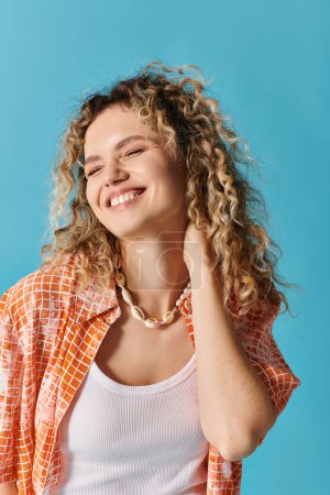 A young woman with curly hair smiles brightly against a vibrant blue backdrop.