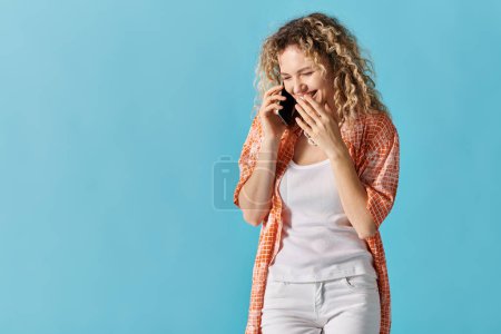 Foto de Mujer con el pelo rizado charlando en el teléfono contra el fondo azul brillante. - Imagen libre de derechos