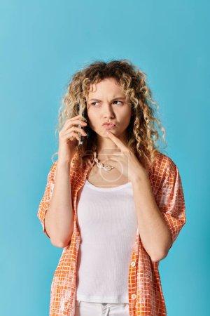 Foto de Young woman with curly hair talking on cell phone against colorful backdrop. - Imagen libre de derechos