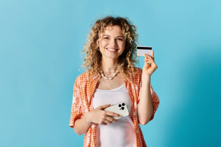 Téléchargez les photos : Femme montrant carte de crédit sur fond bleu vif. - en image libre de droit