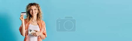 Téléchargez les photos : Femme élégante tenant carte de crédit sur fond bleu vif. - en image libre de droit