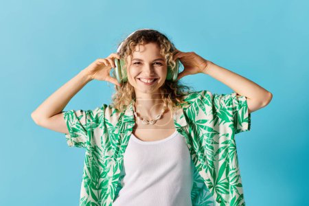 A stylish woman in a green shirt and headphones against a vibrant blue backdrop.