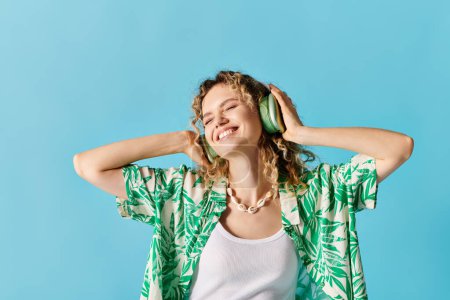Woman in headphones listening to music against blue backdrop.