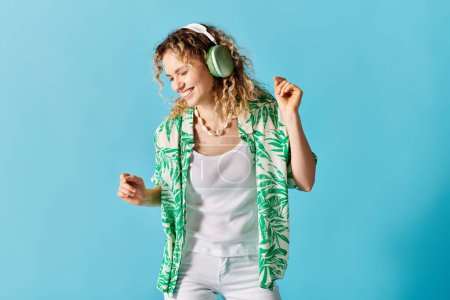 Woman with headphones dancing energetically on blue backdrop.