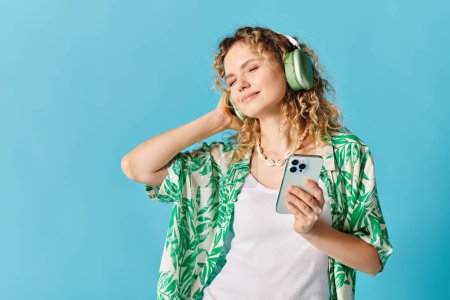 Mujer joven con auriculares escuchando música sobre fondo azul.