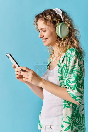 Foto de Mujer con el pelo rizado inmersa en la música a través de auriculares y teléfono. - Imagen libre de derechos
