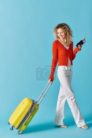Foto de Una mujer con el pelo rizado sosteniendo una maleta amarilla y con pasaporte y billete. - Imagen libre de derechos