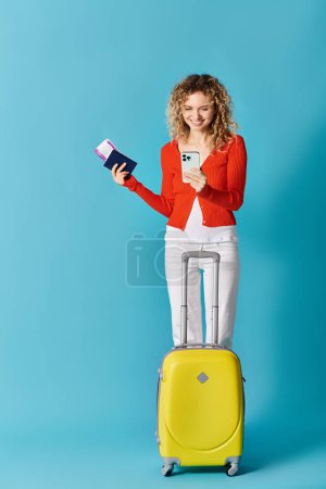 Femme avec valise jaune et téléphone portable