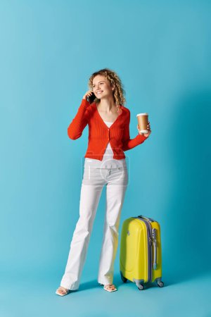 A woman with curly hair holds a cup of coffee and suitcase.